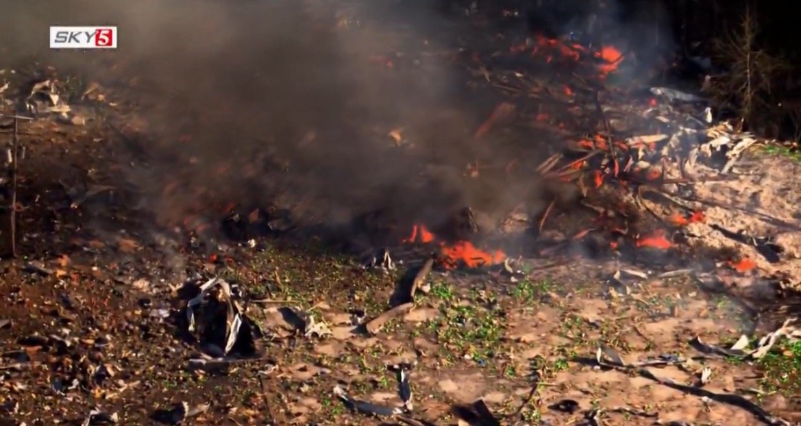 Aerial view of a burning area with smoke and flames, showcasing environmental impact and potential hazards from burning debris.