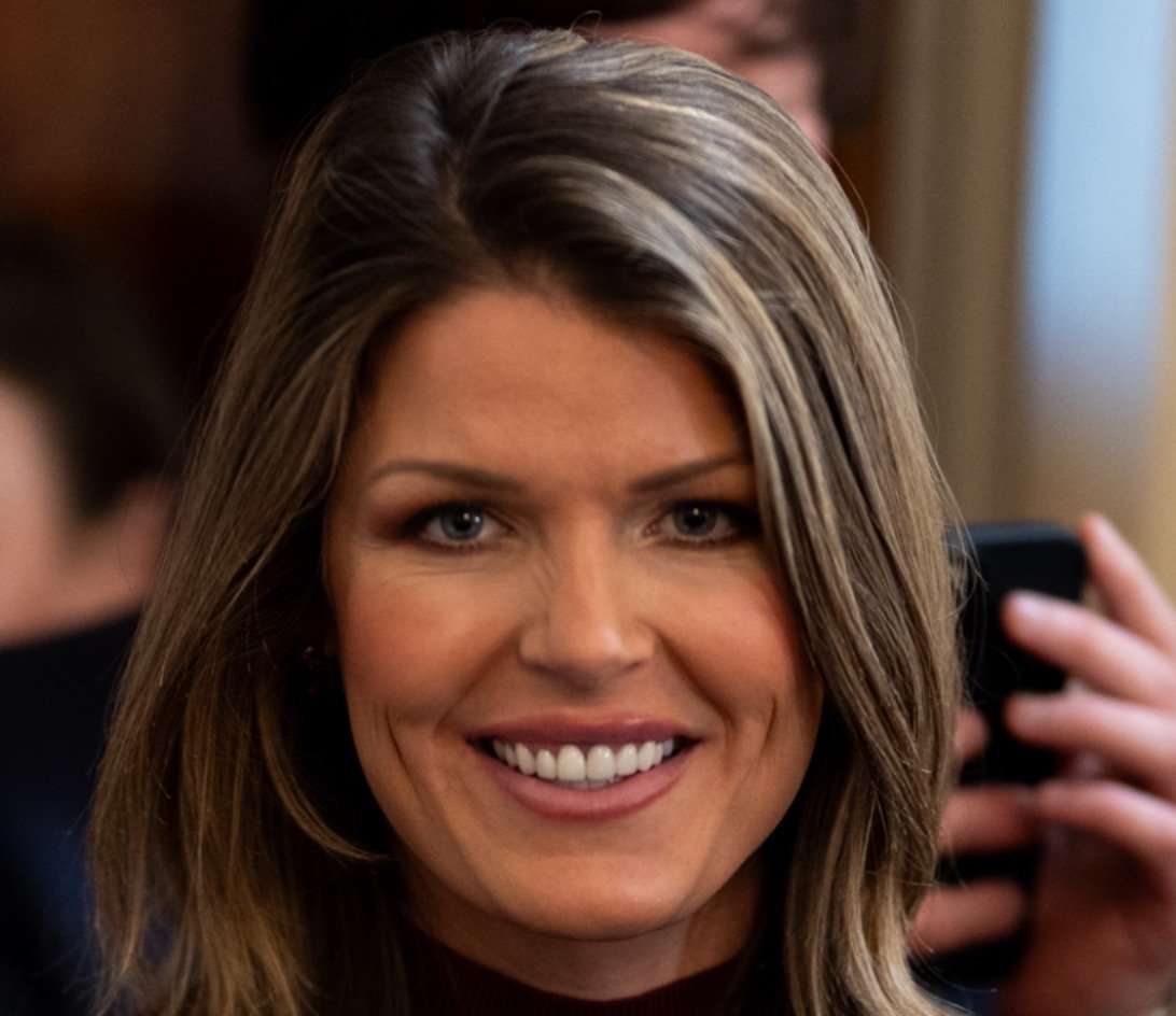 Smiling woman with long, wavy hair and a warm expression, captured in a candid moment at an event.