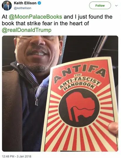 Keith Ellison holding the Antifa Handbook at Moon Palace Books, showcasing the book's bold cover and highlighting its political significance.